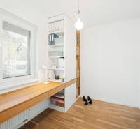 Ein Arbeitszimmer mit einem Holztisch und Regalen in einer Vierzimmerwohnung, Boden mit Holzdekor.