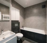 Badezimmer mit Badewanne, Waschbecken und Toilette in einer 4-Zimmer-Wohnung, stilvolle graue Fliesen.