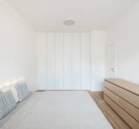 Helles Schlafzimmer in einer 4-Zimmer-Wohnung mit Bett, Kissen und Schrank, Boden mit Holzdekor.
