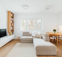 Wohnzimmer mit Sofa, Fernseher, Bücherregal und Esstisch, Boden mit Holzdekor.