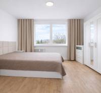 Schlafzimmer mit Doppelbett, Schrank und Holzboden in einer Zweizimmerwohnung.