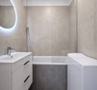 Badezimmer in einer 2-Zimmer-Wohnung mit Badewanne und Waschbecken mit Stauraum.