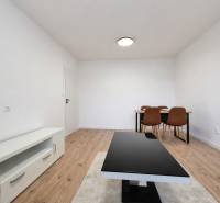 Ein Zimmer in einer 2-Zimmer-Wohnung mit einem Holzboden, einem Tisch und Stühlen.