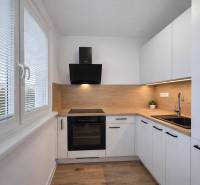 Die Küche einer 2-Zimmer-Wohnung mit einem Boden in Holzoptik und weißen Schränken.