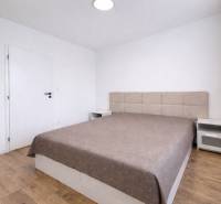 Schlafzimmer in einer 2-Zimmer-Wohnung mit einem großen Bett und einem Boden in Holzoptik.