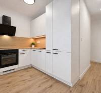Küche mit hellen Möbeln und Boden in Holzoptik in einer 2-Zimmer-Wohnung.