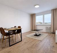 Esstisch und Couchtisch auf einem Boden mit Holzdekor in einer Zweizimmerwohnung.