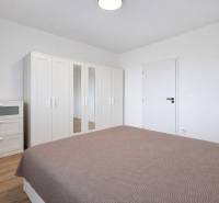 Schlafzimmer mit weißem Schrank und Kommode in einer 2-Zimmer-Wohnung, Boden mit Holzdekor.