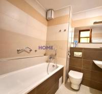 Badezimmer mit Badewanne, Urinal und Waschbecken in einer 2-Zimmer-Wohnung.