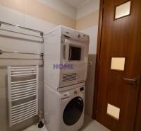 Badezimmer in einer 2-Zimmer-Wohnung mit Waschmaschine und Trockner, weißem Heizkörper an der Wand.