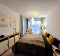 Schlafzimmer mit Bett, dekorativen Kissen und Kommode in einer Zweizimmerwohnung.