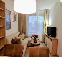 Obývacia izba v 2-izbovom byte s pohodlnou sedačkou a policami.