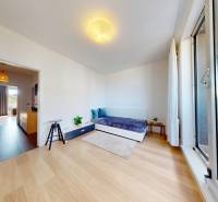 Ein Zimmer in einer 3-Zimmer-Wohnung mit einem Holzboden und einer verglasten Balkontür.