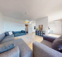Wohnzimmer einer 3-Zimmer-Wohnung mit einem großen Sofa und einem Boden in Holzoptik.