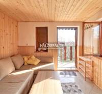 Innenraum des Gartens mit Sofa, Holzverkleidung an den Wänden und offenen Türen zur Terrasse.