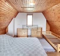 Ein Dachzimmer mit holzverkleideten Dach und Wänden, Bett und Kommode.