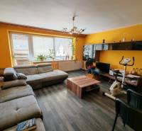 Wohnzimmer eines Einfamilienhauses mit einem Boden in Holzoptik und gelben Wänden.