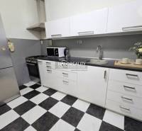 Küche in einer 4-Zimmer-Wohnung mit schwarz-weißem Fliesenboden und weißen Schränken.