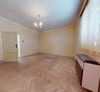 Ein Zimmer in einem Einfamilienhaus mit einem Holzboden und einem einfachen Kronleuchter.