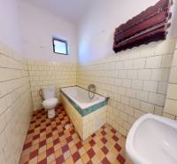 Ein Badezimmer in einem Einfamilienhaus mit Badewanne, Waschbecken und Toilette, gefliest.