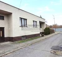 Ein Einfamilienhaus in der Stadt Poltár mit Flachdach und einer Garage an der Straße.