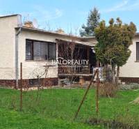 Ein Einfamilienhaus in Poltár, umgeben von Rasen und Bäumen, mit Terrasse und Zaun.