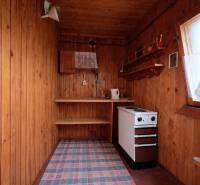 Wände aus Holz, ein Herd und Regale im Inneren mit einem Boden in Holzoptik.