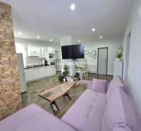 Wohnzimmer eines Einfamilienhauses mit Steinverkleidung und Küchenzeile.