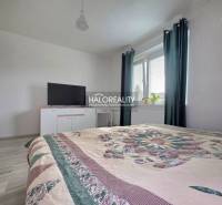 Schlafzimmer in einem Einfamilienhaus mit Bett, Fernseher und Fenster mit dunklen Vorhängen.