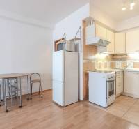 Küche in einer 2-Zimmer-Wohnung mit Holzboden, Esstisch und Kühlschrank.