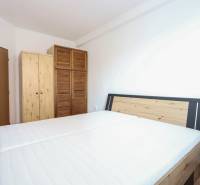 Schlafzimmer in einer 2-Zimmer-Wohnung mit Bett und Holzschränken, Boden mit Holzdekor.