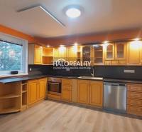 Küche mit orangefarbenen Wänden, Holzschränken und einem Boden mit Holzdekor in einem Einfamilienhaus.