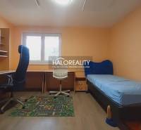Kinderzimmer in einem Einfamilienhaus mit Tisch, Bett und Bürostuhl.