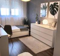 Ein Zimmer in einem Einfamilienhaus mit einem Boden in Holzoptik, Kunstgemälden und dekorativen Blumen.