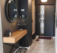 Eingangsbereich mit rundem Spiegel, Holzkonsolentisch und dekorativen Elementen in einem Einfamilienhaus.