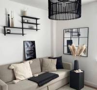 Wohnzimmer in einem Einfamilienhaus mit bequemer Couch, dekorativen Regalen und modernem Kronleuchter.