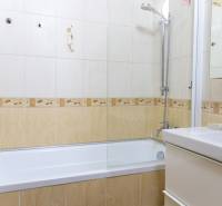 Badezimmer mit Fliesen und Badewanne in einer 4-Zimmer-Wohnung, helle Farben und Duschkopf.