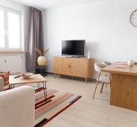 Wohnbereich einer 4-Zimmer-Wohnung mit Fernseher, Sofa, Tisch und Boden in Holzoptik.