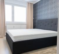 Schlafzimmer in einer 4-Zimmer-Wohnung mit Bett, Tapete, Fenstern und Vorhängen, Boden mit Holzdekor.