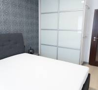 Schlafzimmer in einer 4-Zimmer-Wohnung mit gepolstertem Bett, Tapete und Einbauschrank.