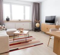 Wohnzimmer in einer 4-Zimmer-Wohnung mit Holzboden, Sofa und Fernseher.