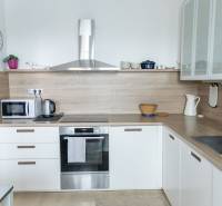 Küche mit eingebauten Geräten in einer 4-Zimmer-Wohnung, Boden mit Holzdekor, helle Küchenzeile.