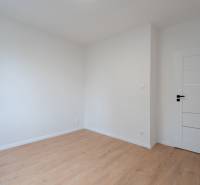 Ein Zimmer in einer 3-Zimmer-Wohnung mit einem Boden in Holzoptik und weißen Wänden.