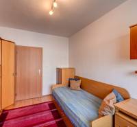 Ein Zimmer in einer 3-Zimmer-Wohnung mit Schränken, einem Bett und Holzschränkchen.
