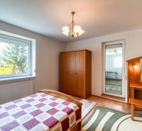 Schlafzimmer in einer 3-Zimmer-Wohnung mit Holzboden, einfachem Möbel und großem Fenster.
