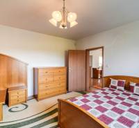 Schlafzimmer in einer 3-Zimmer-Wohnung mit Holzmöbeln und einem Bett mit kariertem Überwurf.