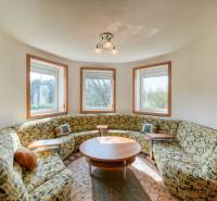 Okrugles Zimmer in einer 3-Zimmer-Wohnung mit Sofa, zentralem Tisch und Fenstern mit Aussicht.