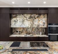 Eine Küche mit markanten Marmoroberflächen und dunkler Holzverkleidung in einer Vierzimmerwohnung.