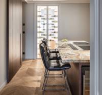 Küche in einer 4-Zimmer-Wohnung mit Bartresen, Stühlen und Boden mit Holzdekor.