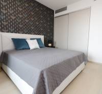 Schlafzimmer mit Bett, gemusterte Wand, Boden mit Holzdekor, 2-Zimmer-Wohnung.